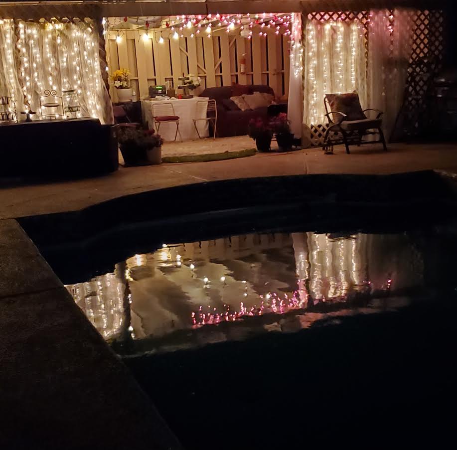 Romantic poolside evening setup with twinkle lights and lounge seating